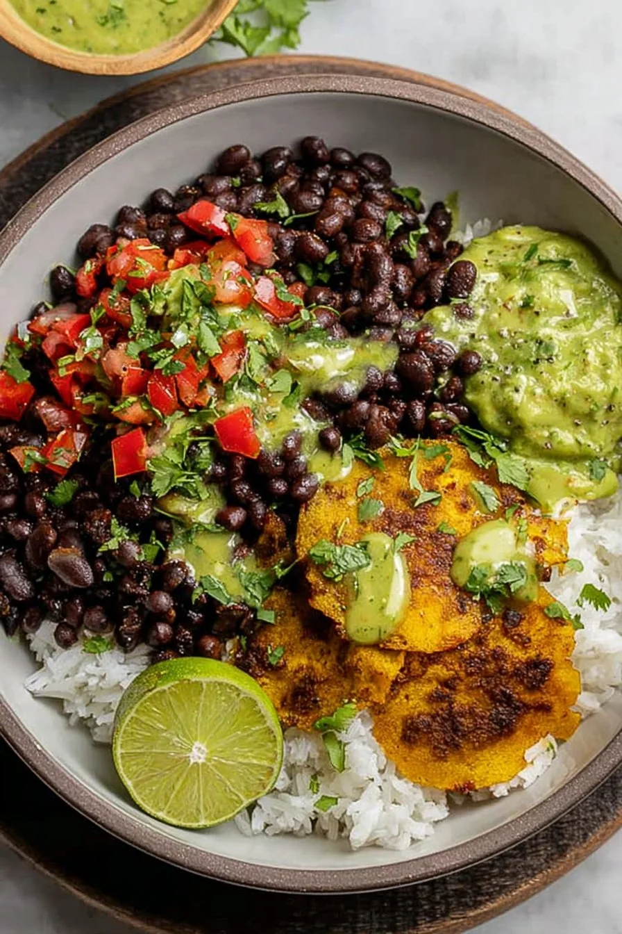 Vibrant bowl filled with black beans, rice, veggies, and lime wedges