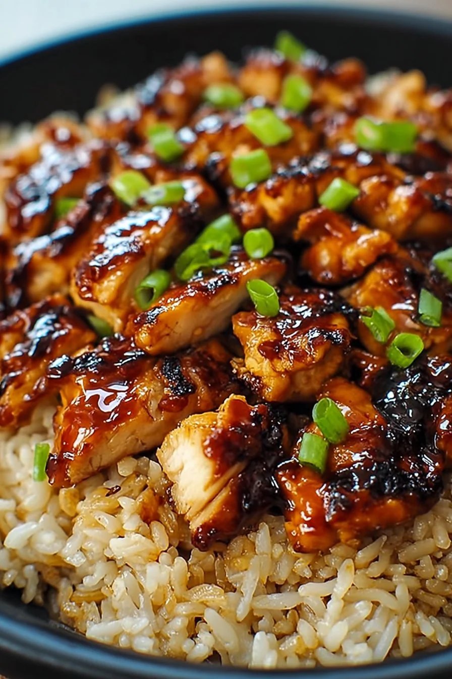 A bowl of Honey BBQ Chicken Rice topped with fresh herbs and a drizzle of sauce.